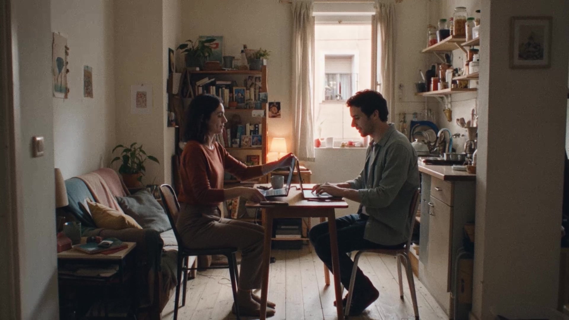 Pareja trabajando con portátiles en la mesa de una cocina