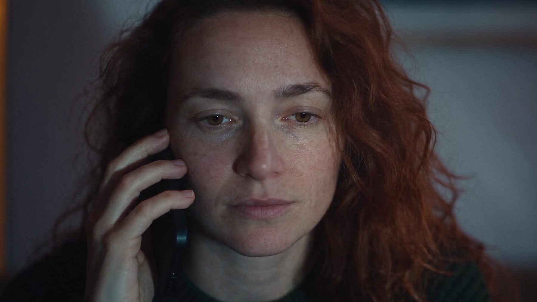Mujer al teléfono con los ojos húmedos